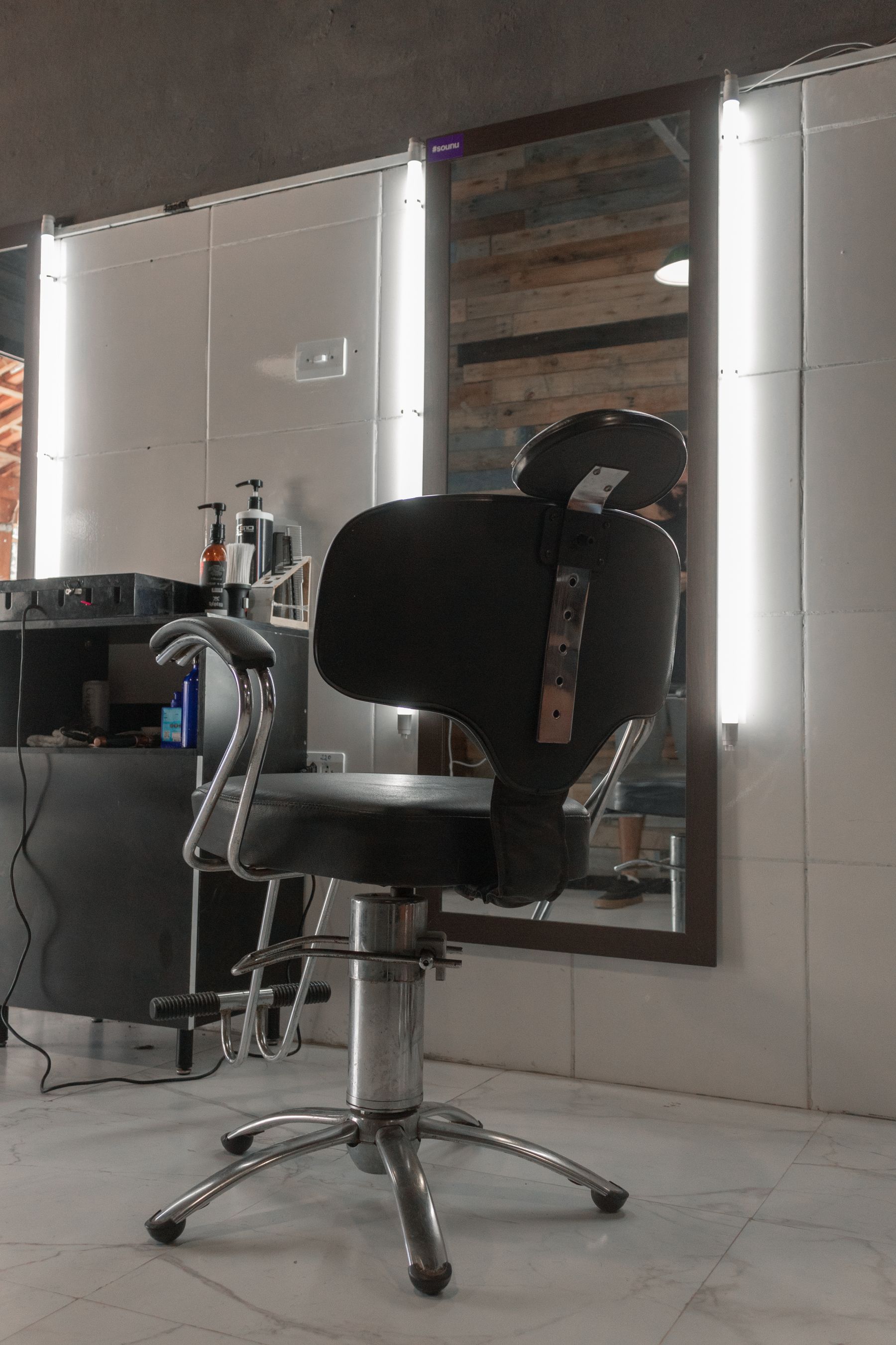 O interior da Barbearia Aresta: cadeiras de barbeiro, espelhos e bancada de concreto.