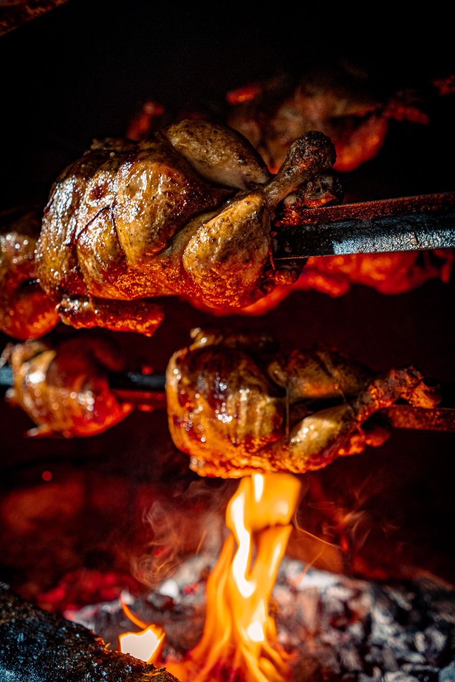 Frango inteiro assando em fogo de chão, à moda tradicional