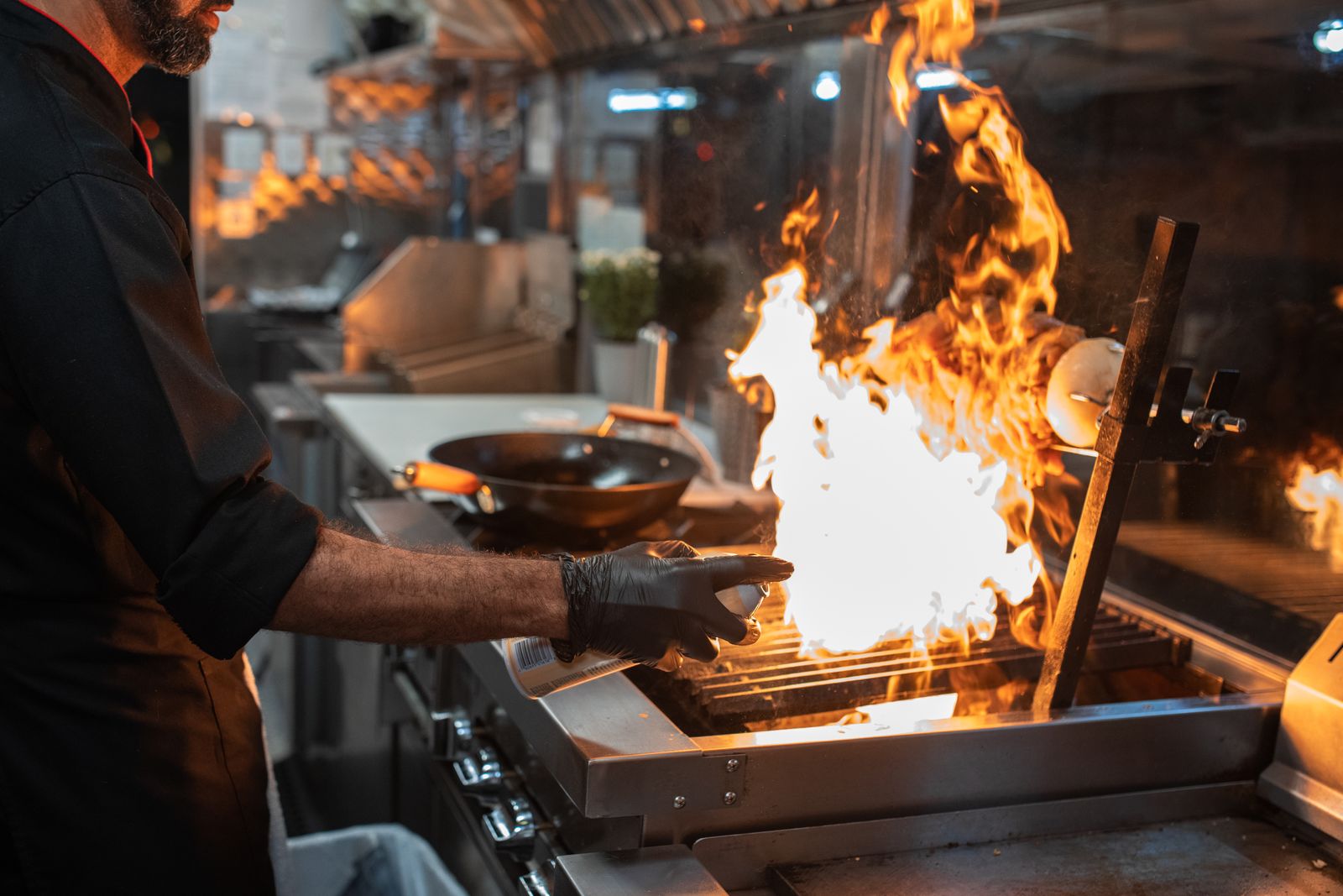 Chef grelhando carne sobre chama aberta na cozinha profissional