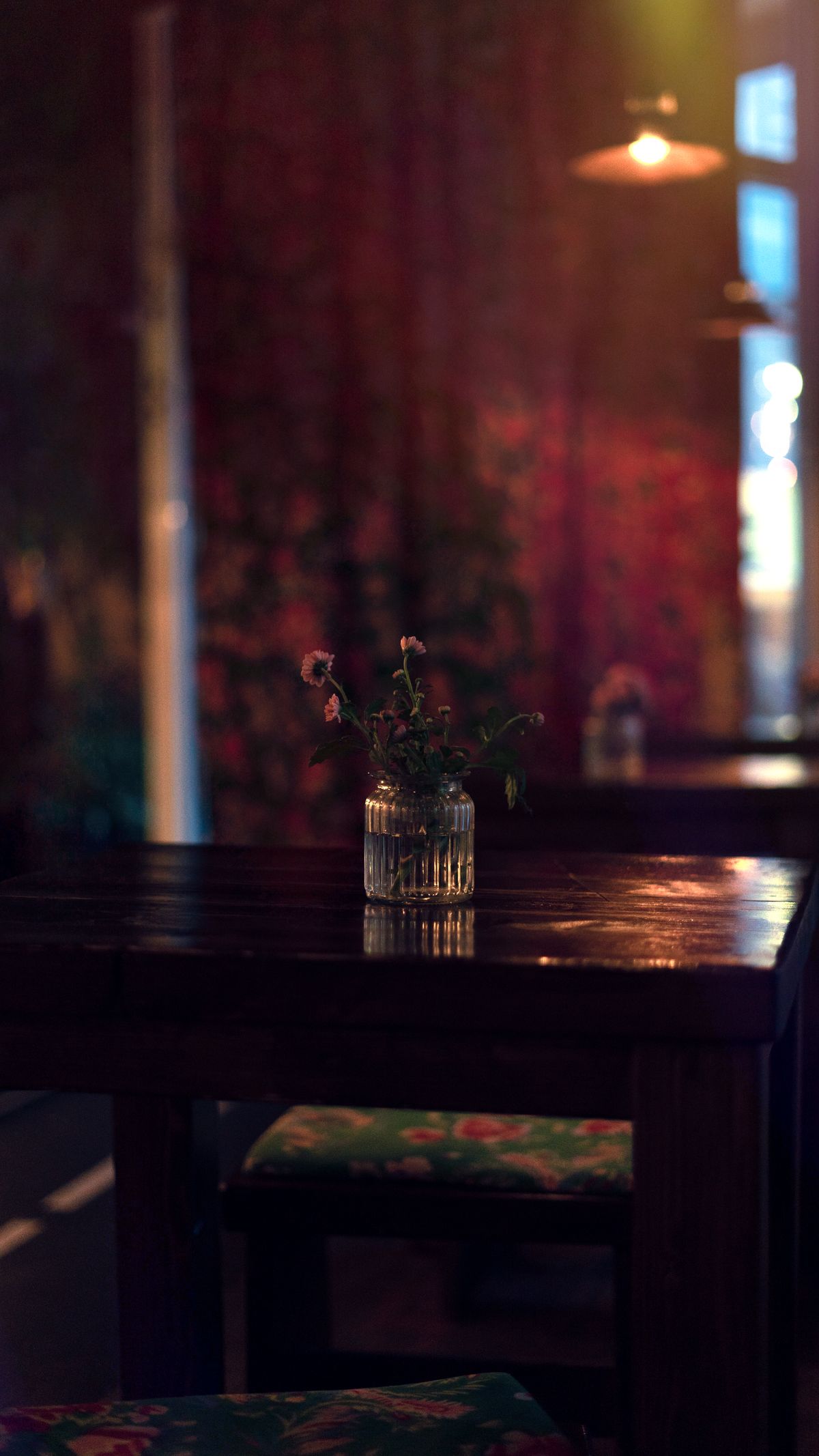 Salão do restaurante com luz baixa e mesa posta em madeira