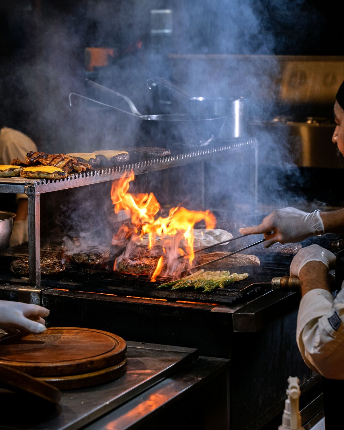 Cozinheiros grelhando carnes entre chamas na cozinha do restaurante
