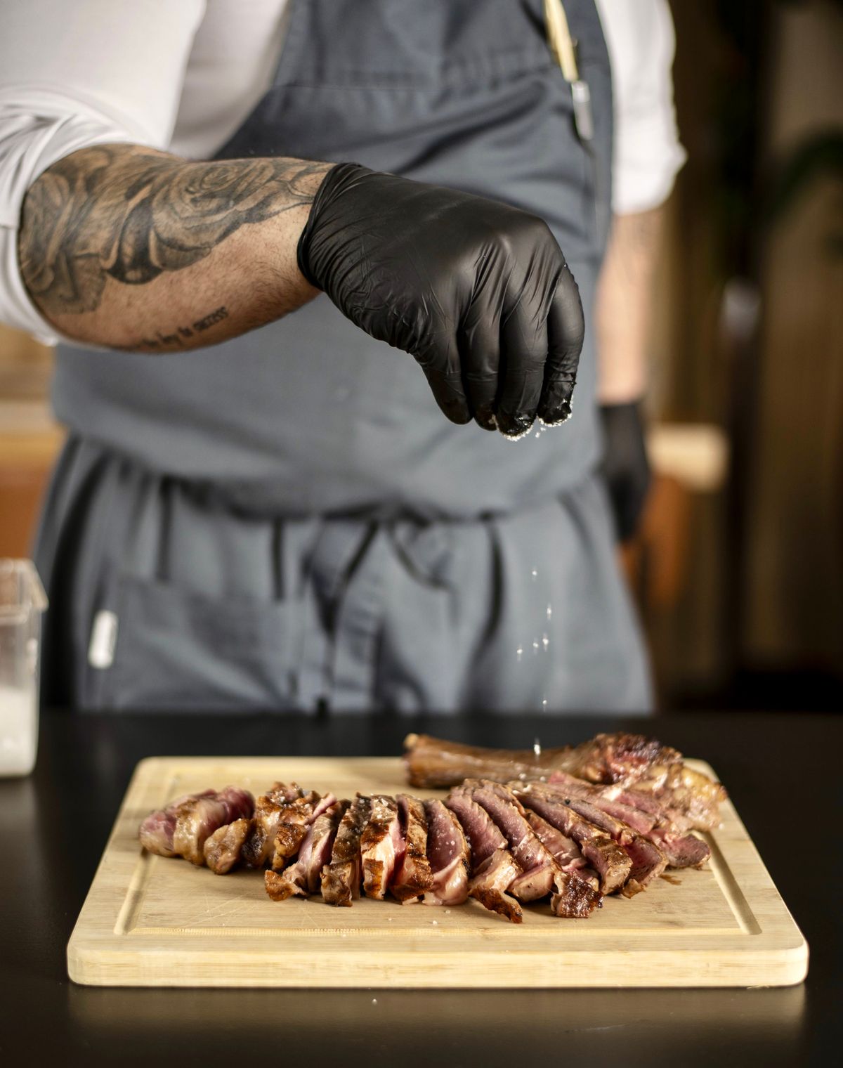Chef temperando fatias de carne grelhada com sal grosso