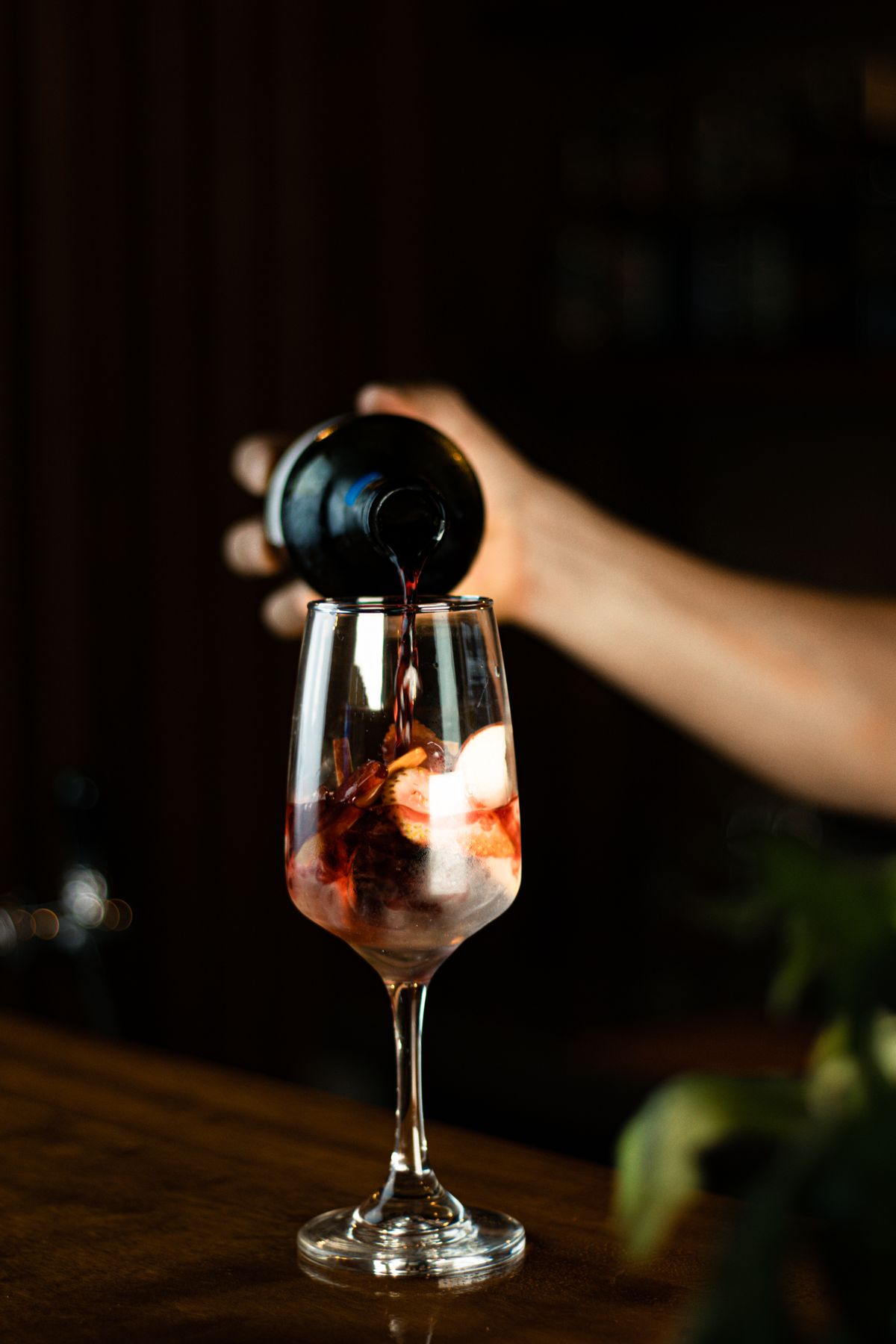 Vinho tinto sendo servido na taça sob luz quente do balcão