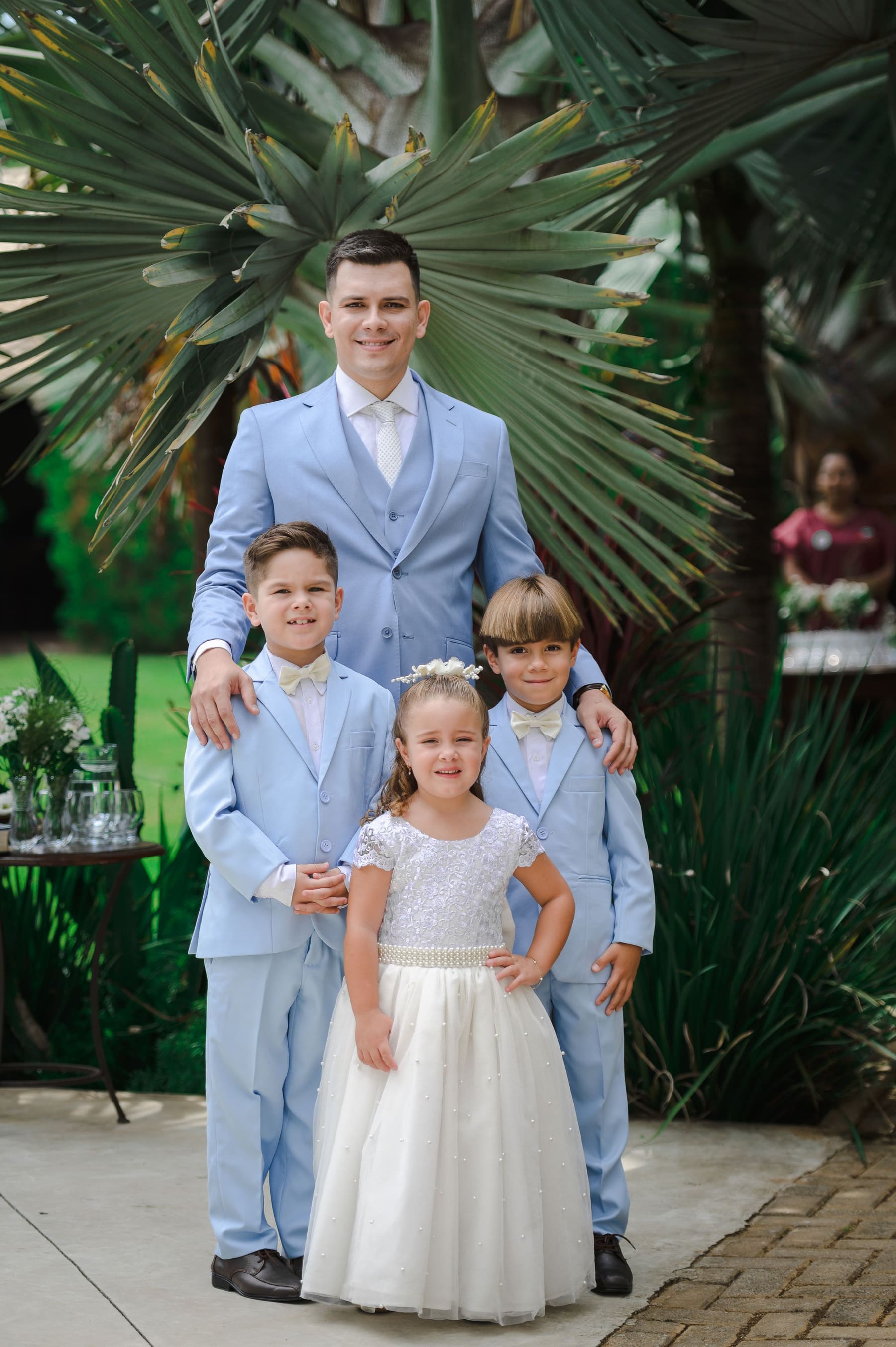 Um pai com os três filhos pequenos, todos arrumados para o casamento.