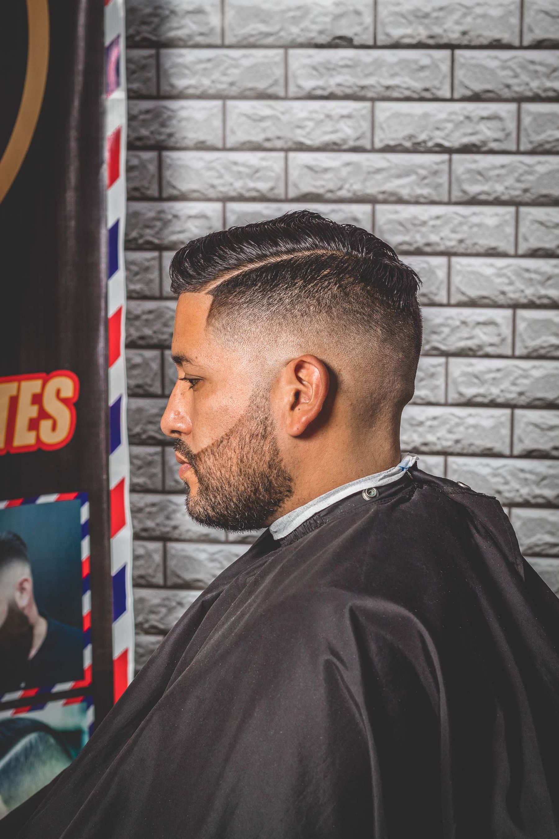 Cliente com degradê fresco, de frente para o espelho da barbearia.