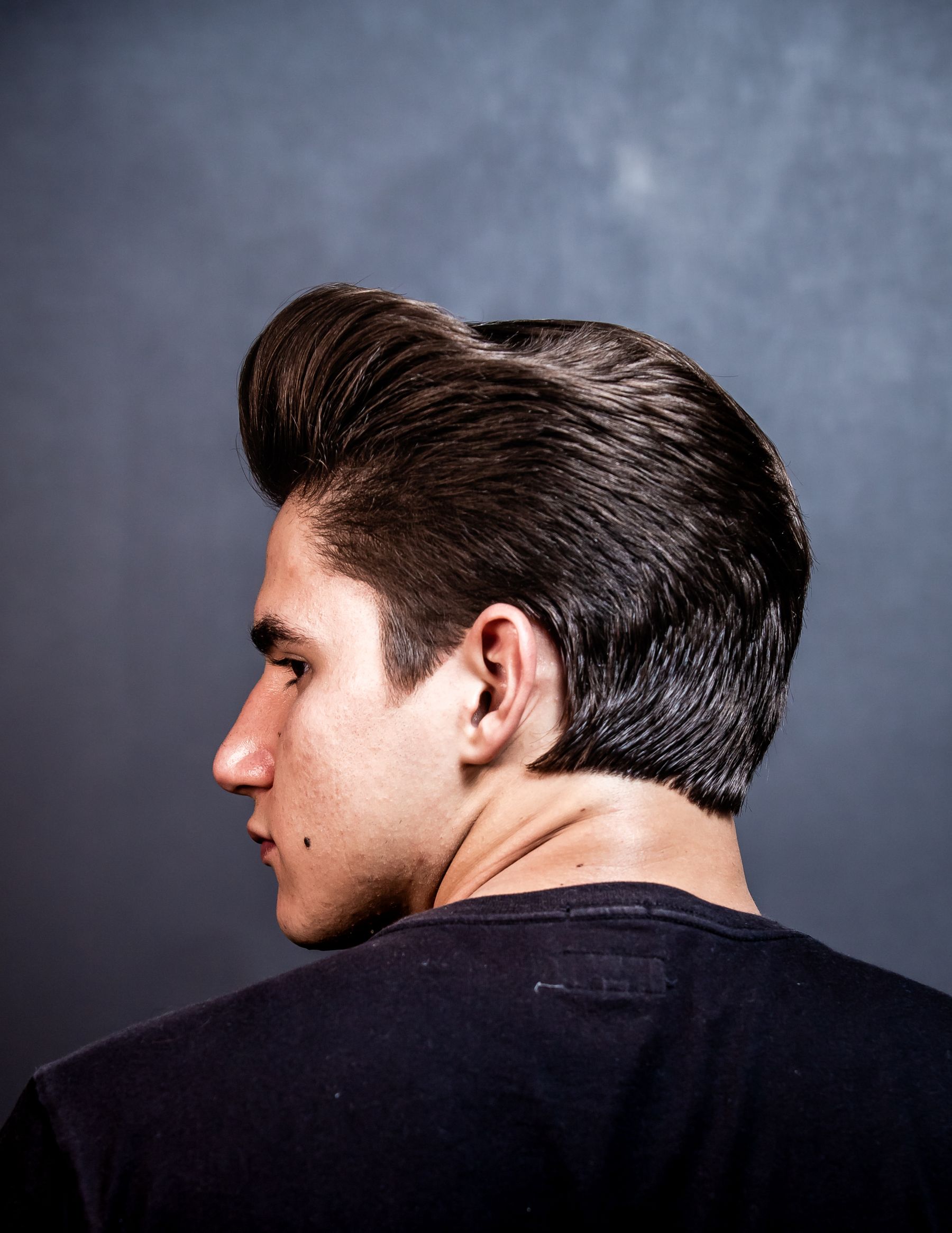 Cliente com corte social clássico e risca marcada, em retrato de perfil.