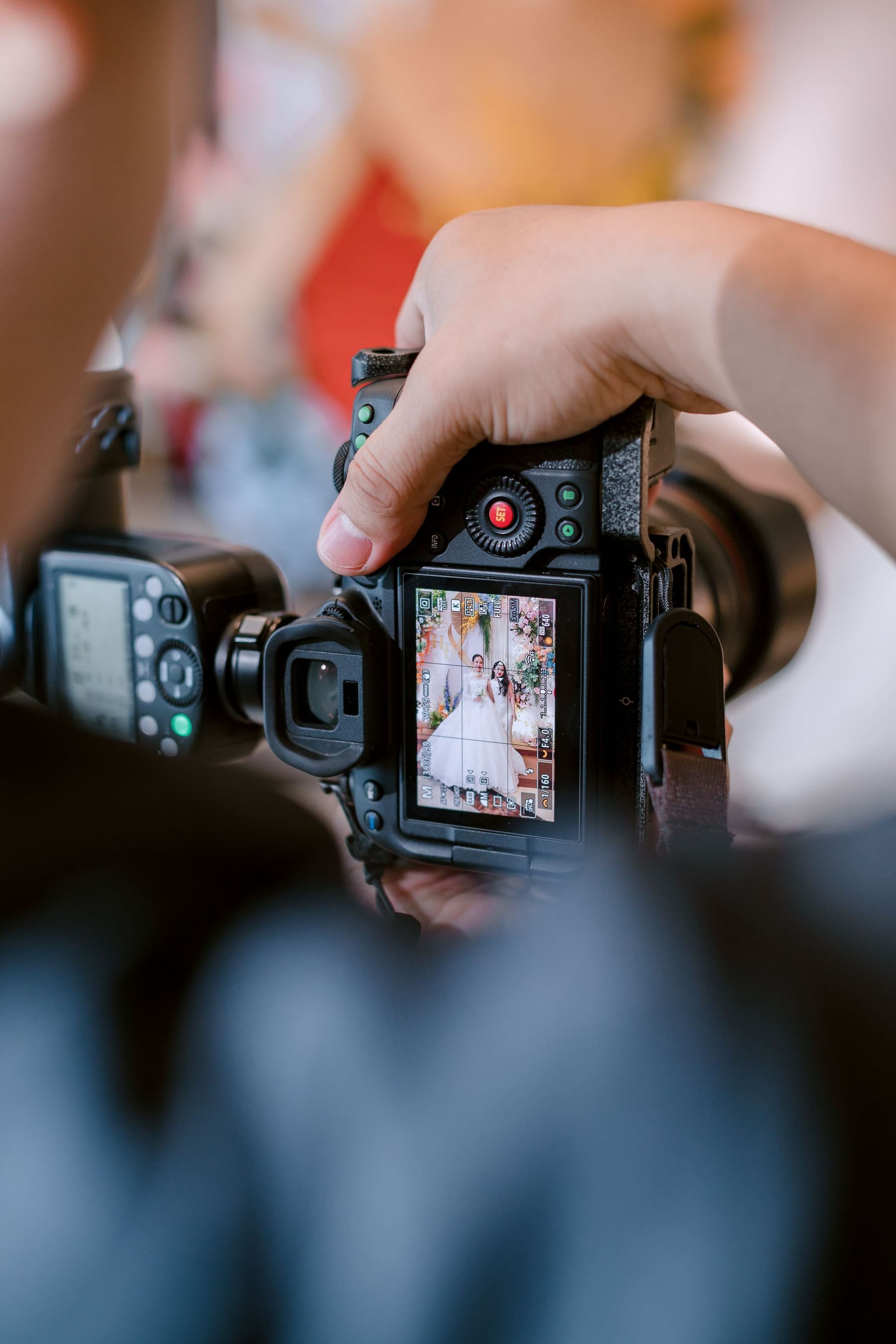 Mãos segurando a câmera, revendo no visor uma foto do casal durante o casamento.