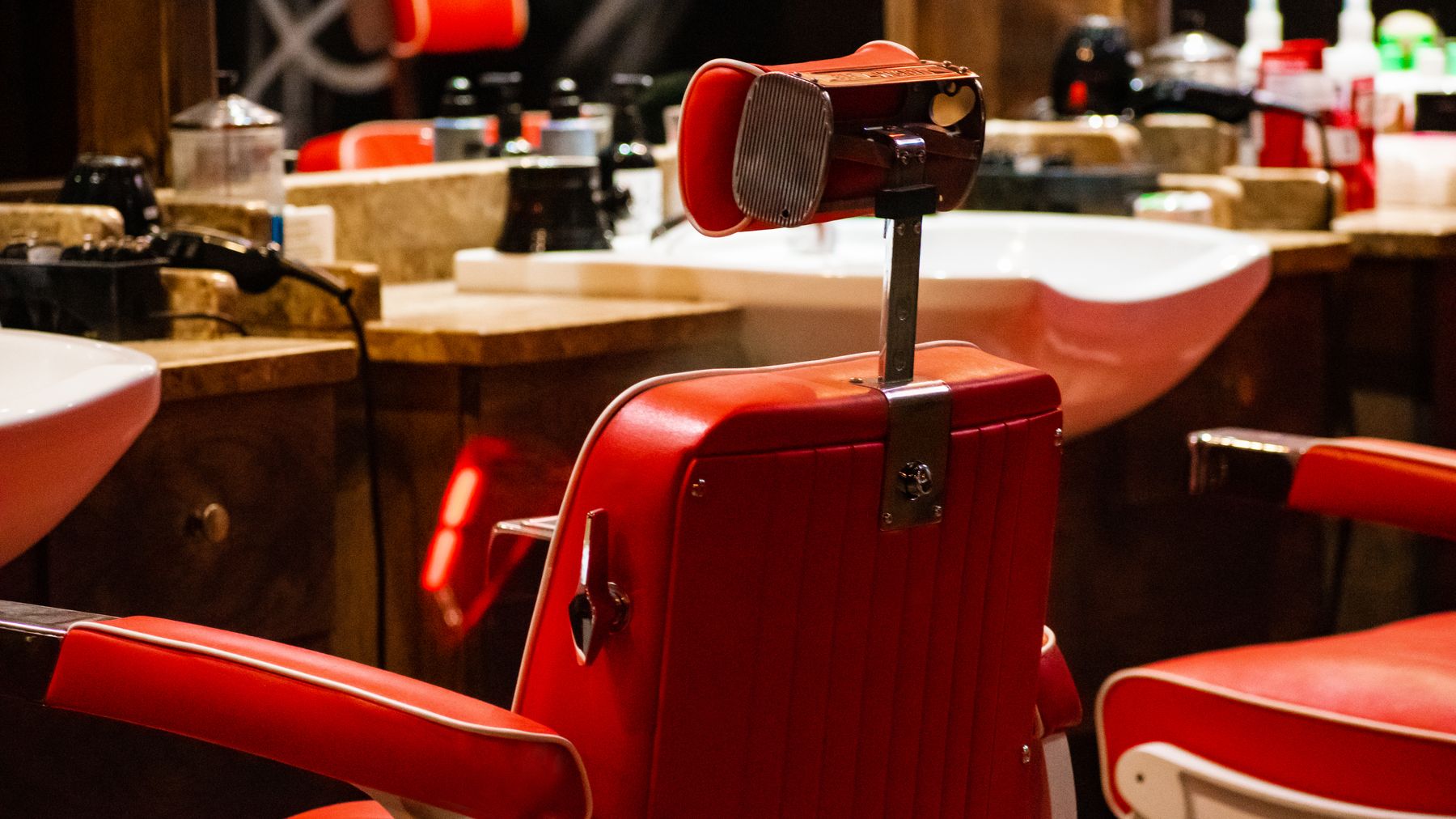 Uma cadeira de barbeiro vintage vazia, em couro vermelho, à espera do próximo cliente.