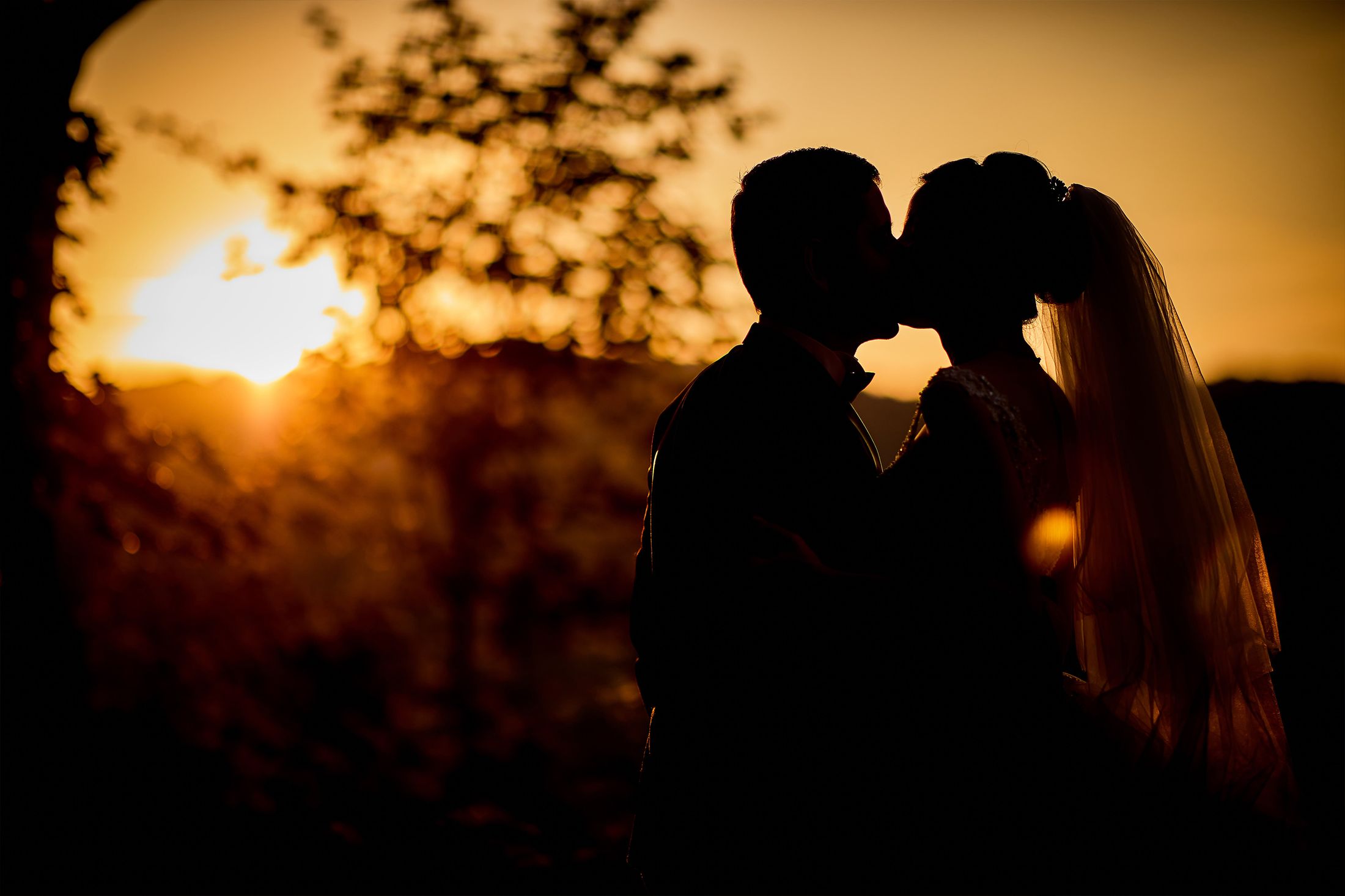 Um casal recortado contra o sol do fim de tarde, num campo aberto.