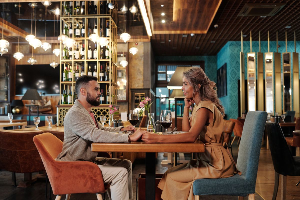 Casal brindando com vinho em jantar à meia-luz no restaurante