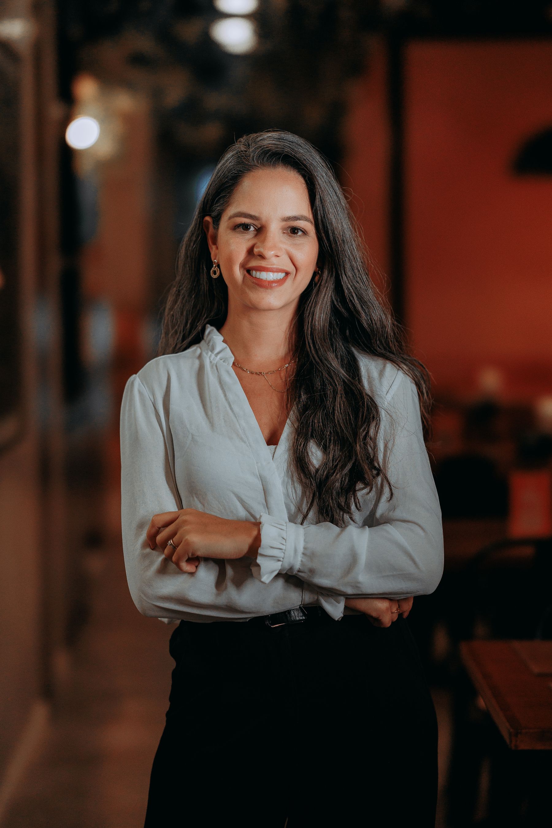 Renata Vasconcelos, sentada junto a uma janela, olhando com calma para a câmera.